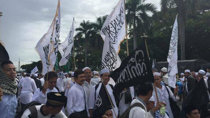 Protester hold flags bearing the Islamic testament of faith - one of them upside down - at the rally in Jakarta. Photo: Jewel Topsfield