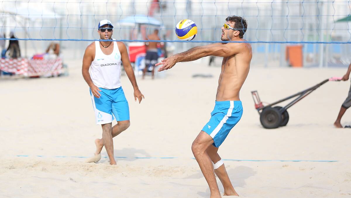 Olympic volleyball players Adrian Carambula and Alex Ranghieri of Italy practice on Copacabana Beach while workers set up for the Olympic Volleyball games on July 30, 2016 in Rio de Janeiro, Brazil. Photo: Joe Scarnici/Getty Images