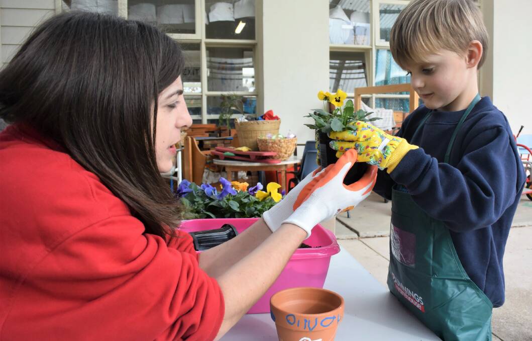 NEW GROWTH: Sarah Campisi of Bunnings teaches Oliver McMaster how to plant a flower for Planet Ark’s Schools Tree Day. Picture: DAINA OLIVER