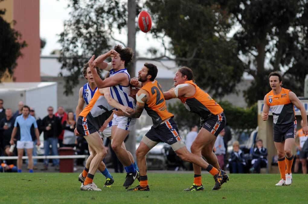 CROWDED: Roo Sam Brewer gets a handball away after being tackled by two Giants. 