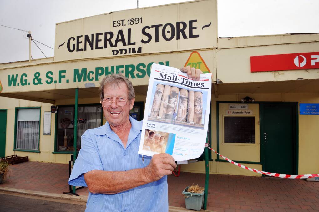 W.G. and S.F. McPherson general store's Wavell McPherson with a copy of the Mail-Times featuring Brim's silos. 