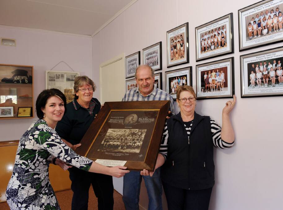 RESTORED: Emma Kealy and Wonwondah's Jenny Brauer, Chris Guest and Jeanette Guest with tennis and football premiership photos. Picture: PAUL CARRACHER