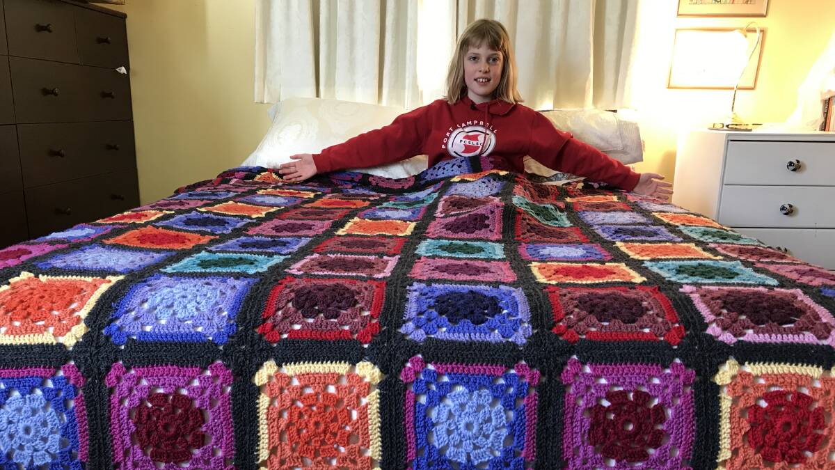 WINTER WARMTH: Annie snuggles into this pure wool crocheted bedspread being raffled by the Pomonal Progress Association for the Fiona Elsey Cancer Research Institute. Picture: CONTRIBUTED