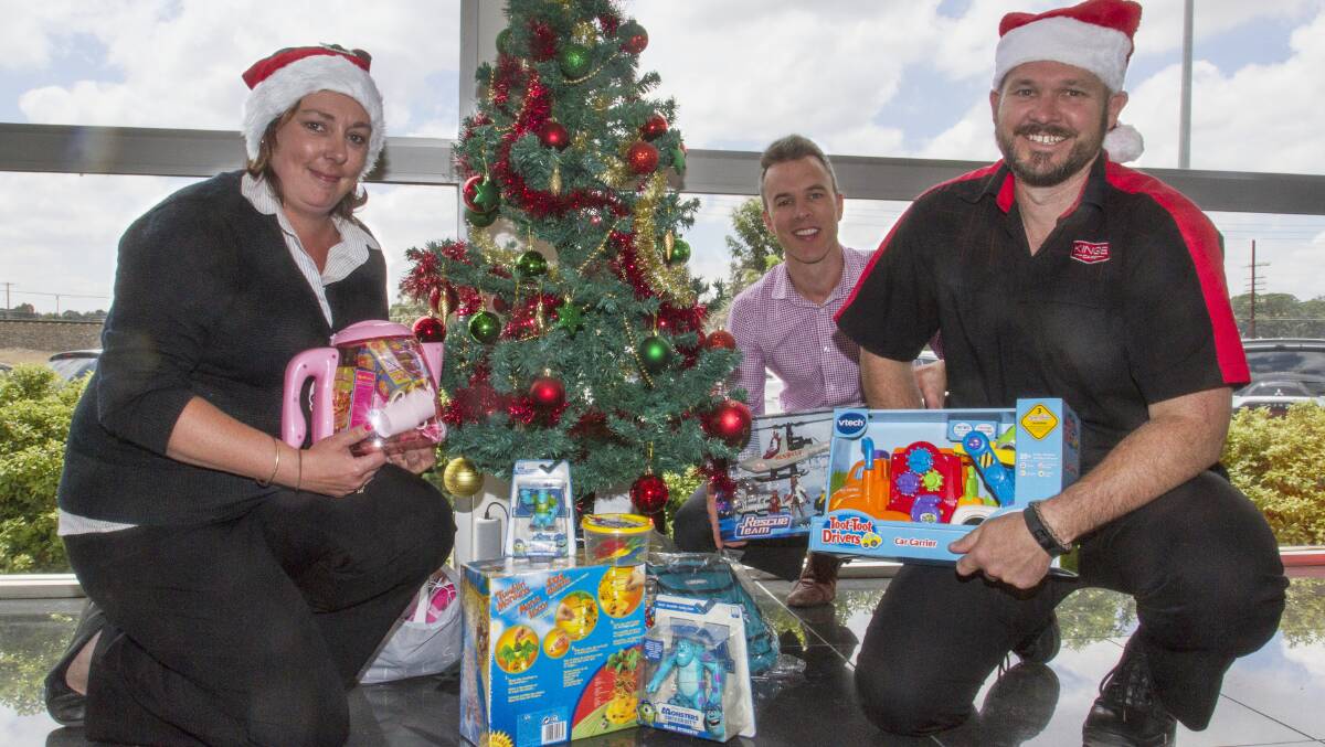 GIVING: Rachel Ralph, Michael Smith and John Grayling at the Ararat Emergency Relief Committee Toy and Gift Christmas Appeal tree at Ararat Kings Cars. Picture: PETER PICKERING 