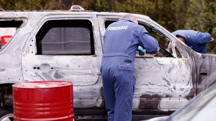 Forensic investigators inspect the burnt out vehicle. Photo: Darrian Traynor