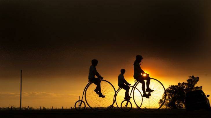 Dan Bolwell goes for a ride on his hand-crafted penny farthing with his children Molly and Caleb.  Photo: Jason South