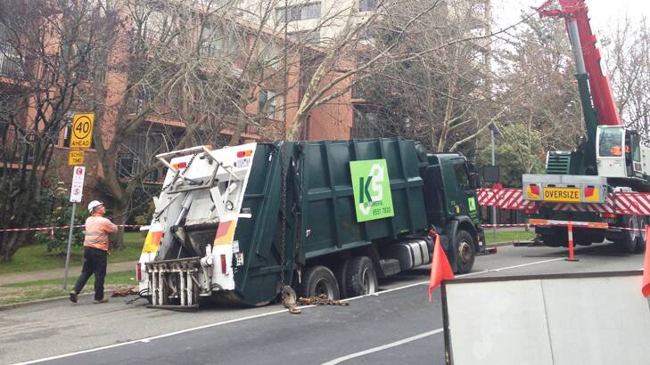 A crane lifts the sunken garbage truck out of the hole on Orrong Road, Armadale. Photo: Jessica Kerstjens