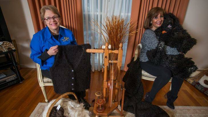 Marion Wheatland (left) holds a vest she spun and knitted from the fur of poodle Mango, held by his owner, May Battista. Photo: Meredith O'Shea