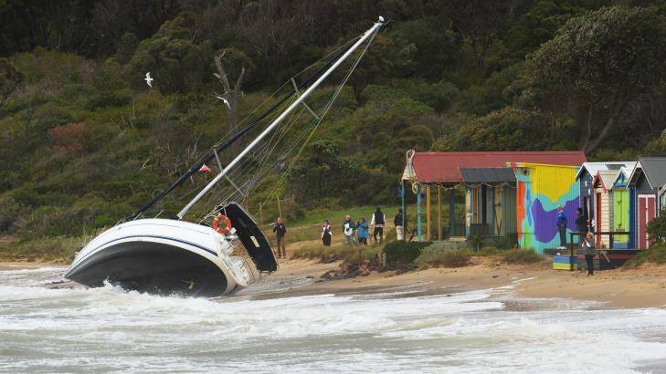 A yacht is washed ashore as large waves hit the Mornington pier during a storm.  Photo: Joe Armao