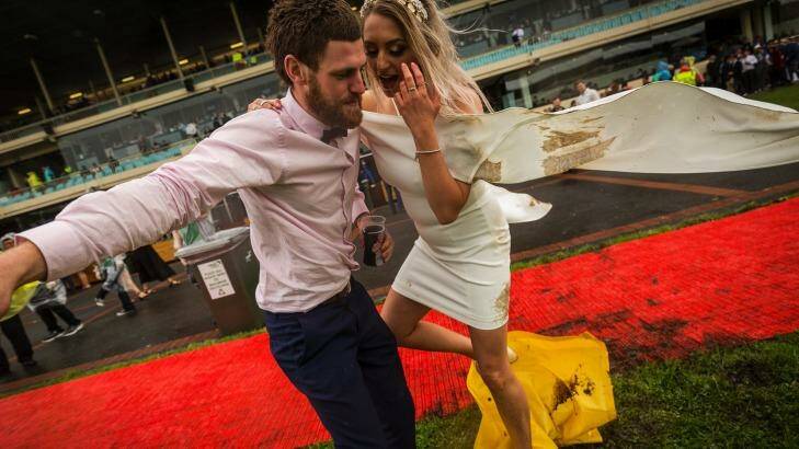 Francis Kavanagh helps his girlfriend Tiarne Coxhill across a muddy area at Cox Plate day at Moonee Valley racecourse. Photo: Chris Hopkins