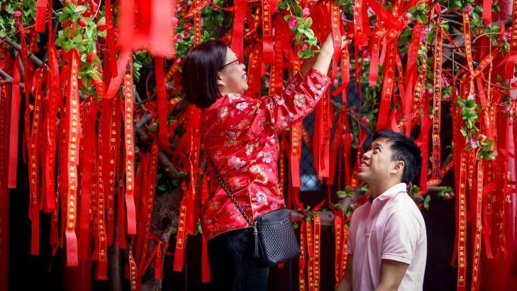 Pody Tung, left, and son Jonathan Chang hang a ribbon on the wish tree at Bright Moon Buddhist Temple during 2016 Lunar New Year celebrations. Photo: Eddie Jim