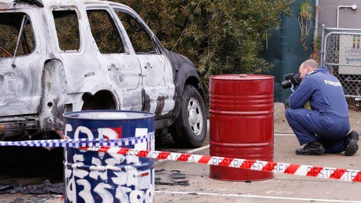 Forensic investigators photograph the burnt out car. Photo: Darrian Traynor