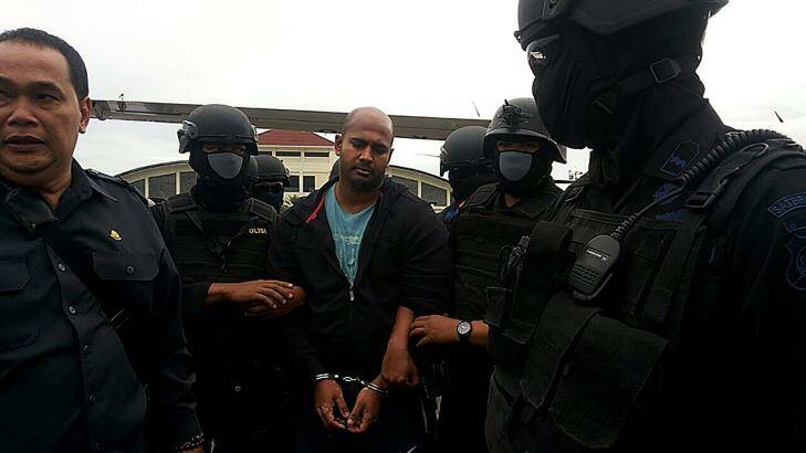 Myuran Sukumaran is surrounded by masked security personnel upon arriving at Cilacap airport.