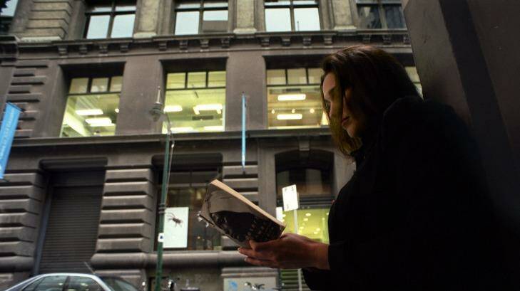 A woman reads a book in front of the Flinders Lane building in 2002, before it became a library.  Photo: Ken Irwin