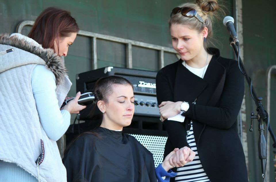 SUPPORT: Hairdresser Calinda Barker shaves Bree Pickering's head at the Belinda Scott family fun day at Stawell Racecourse on Sunday. Mrs Scott, who is battling bowel and liver cancer, holds her friend's hand during the process. Picture: CONTRIBUTED