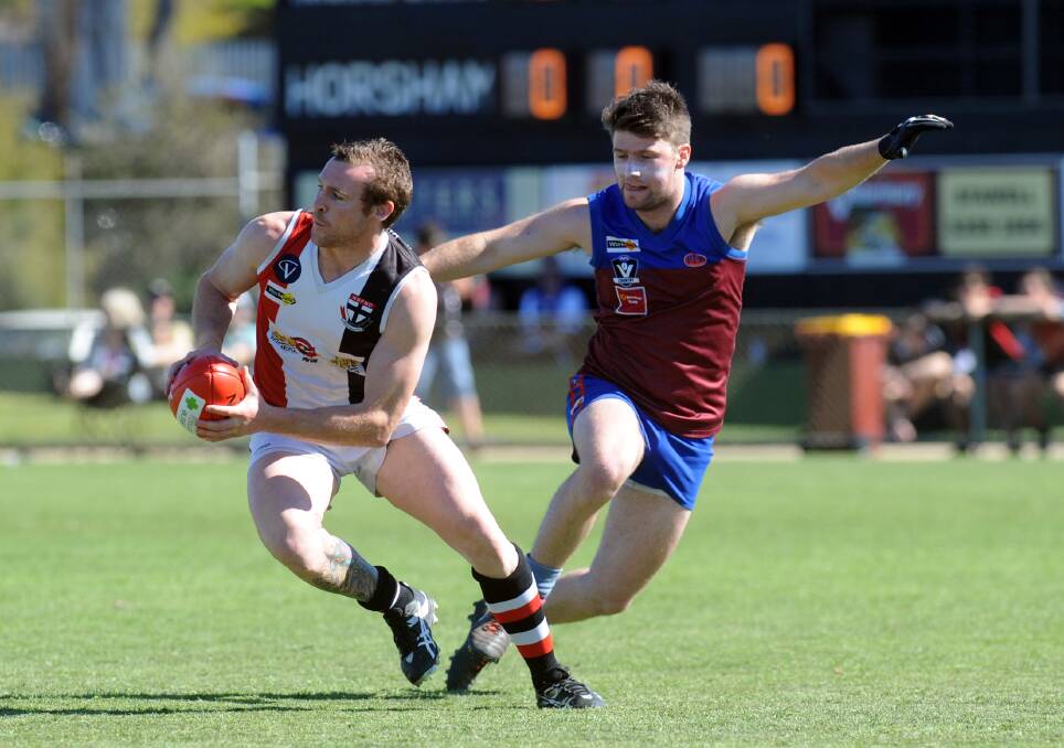 RIVALS: Horsham Saint Patt Knott evades Horsham's Darcy Taylor in the 2013 Wimmera Football League grand final. The cross-town rivals will play each other on Anzac Day in 2015. Picture: PAUL CARRACHER