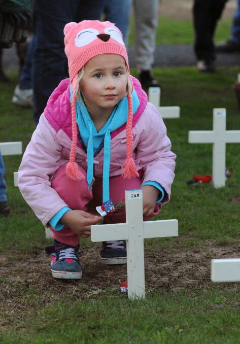 Nelly Driller, 4, places a poppy at a cross at Horsham Anzac Day dawn service. 