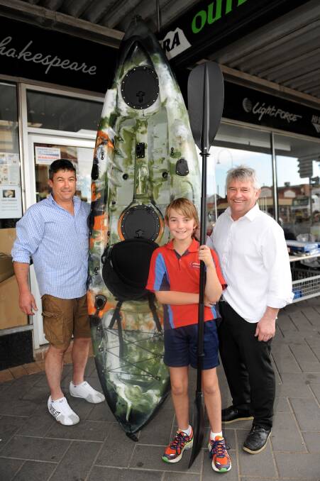 JUNIOR PRIZE: Wimmera Outdoors’ Paul Lewis, left, and Gary Jelly, and junior angler Ned Pilmore with a fishing kayak that is part of the Dimboola Fishing Classic’s junior first prize. Picture: SAMANTHA CAMARRI