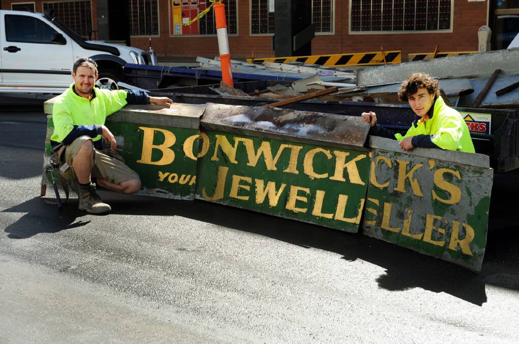 FEBRUARY: Locks Constructions builders Patrick McDonald and Brady Jenner with an old sign from Bonwick's Jeweller.