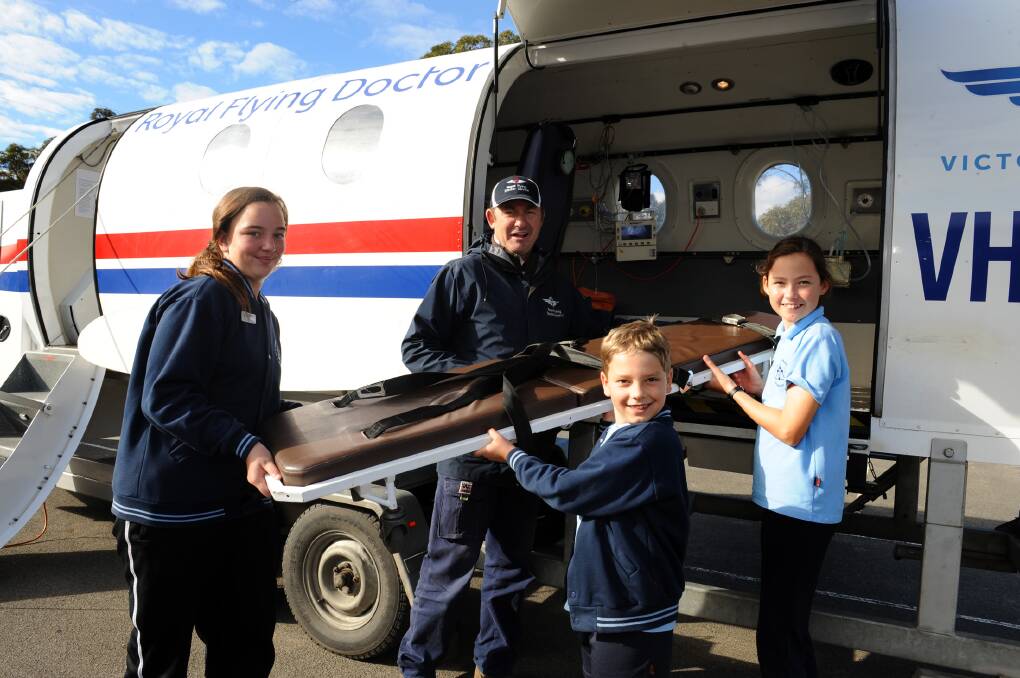 HANDS-ON LEARNING: St Peter’s Lutheran School students Olivia Lehmann, Zachary Jorgenson and Isabella Nuske help Royal Flying Doctor Service’s Tom Tyan load a mock plane fuselage as part of a school education program. Picture: PAUL CARRACHER