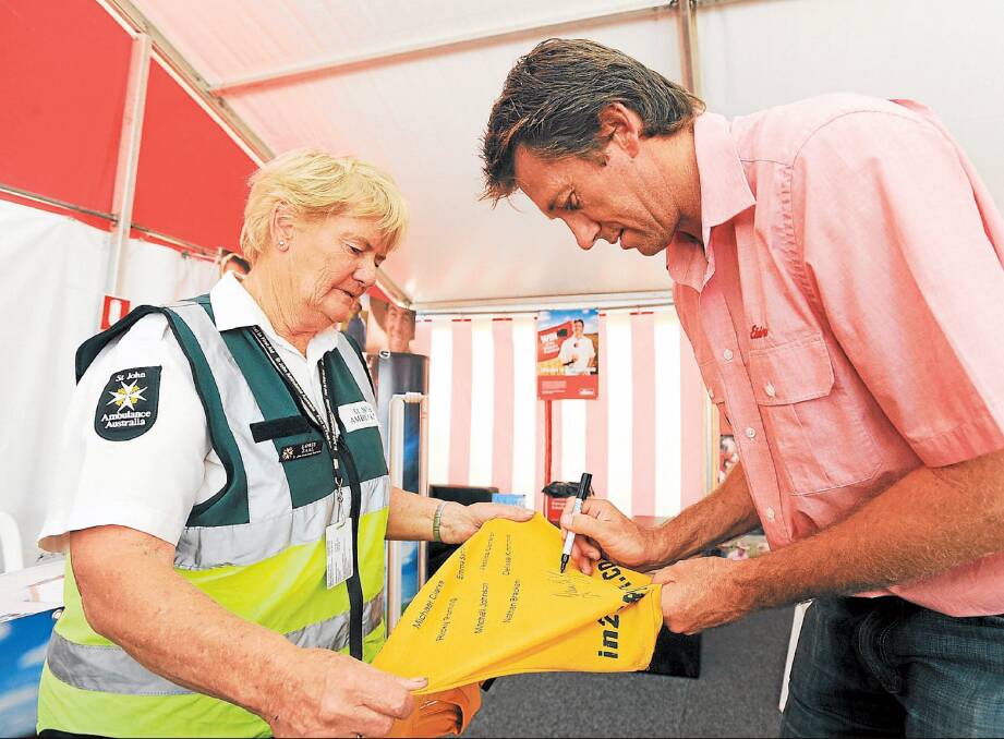 Former Australian Test cricketer Glenn McGrath autographs a shirt for St John Ambulance Australia member Loris Zaal during day one of the Wimmera Machinery Field Days. Mr McGrath is a guest of Elders. Picture: AMY PYSDEN
