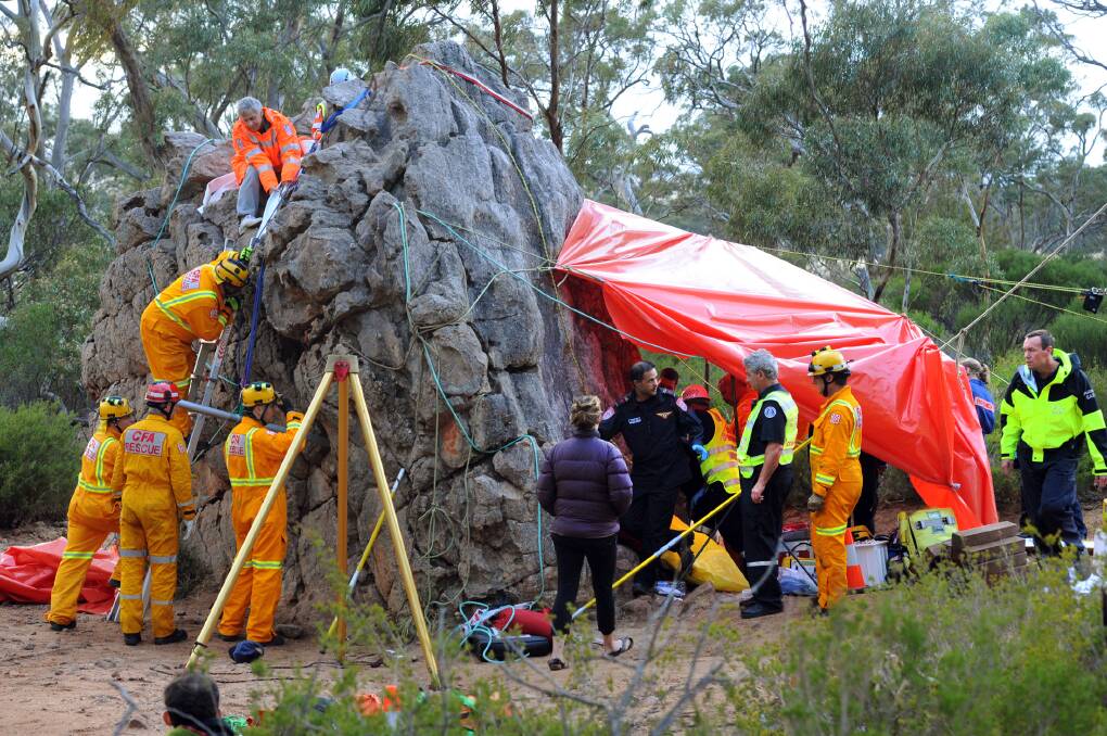 BETWEEN A ROCK AND A HARD PLACE: Rescue crews work on a large boulder at the base of Mt Arapiles early Tuesday morning. A man is tightly wedged in a narrow crevice behind the tripod. Climbers refer to the crevice as the Squeeze Test. Pictures: PAUL CARRACHER