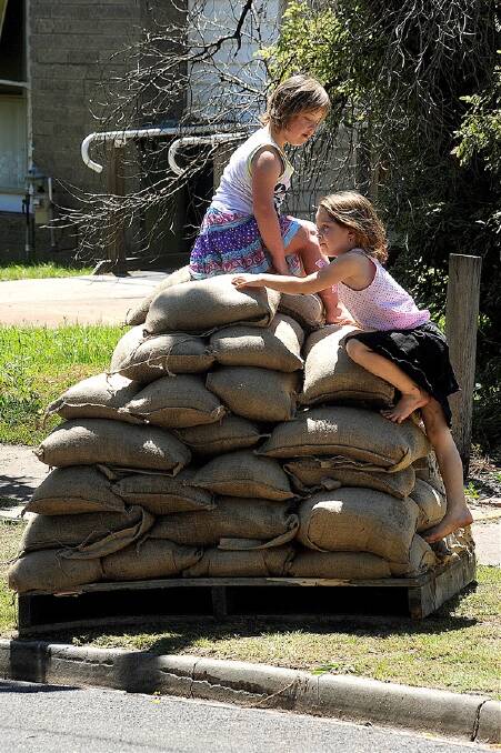 FUN FOR THE MOMENT: Isabella Hourigan, 8, and Montanna Pickering, 5, play on sandbags in Gillespie Street, Horsham, yesterday. Picture: PAUL CARRACHER