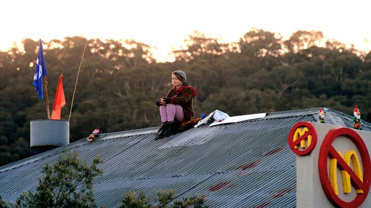A protester sits on the roof of the proposed McDonald's in Tecoma on Wednesday. Photo: Penny Stephens