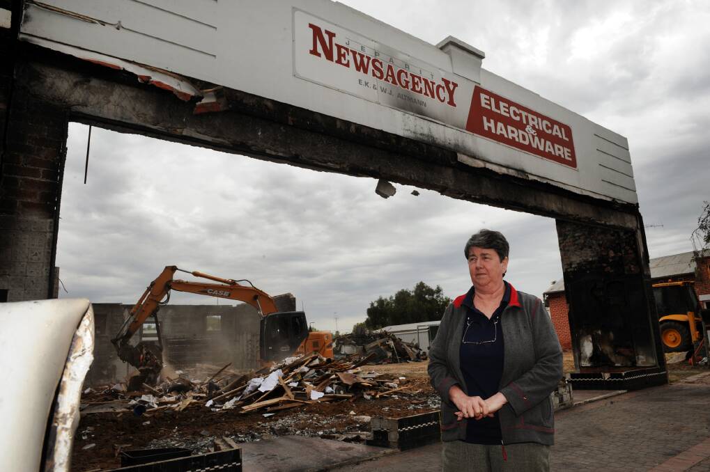 Rhonda Holden, owner of Jeparit Newsagency, watches the burnt-out building get demolished last week.  Picture: PAUL CARRACHER