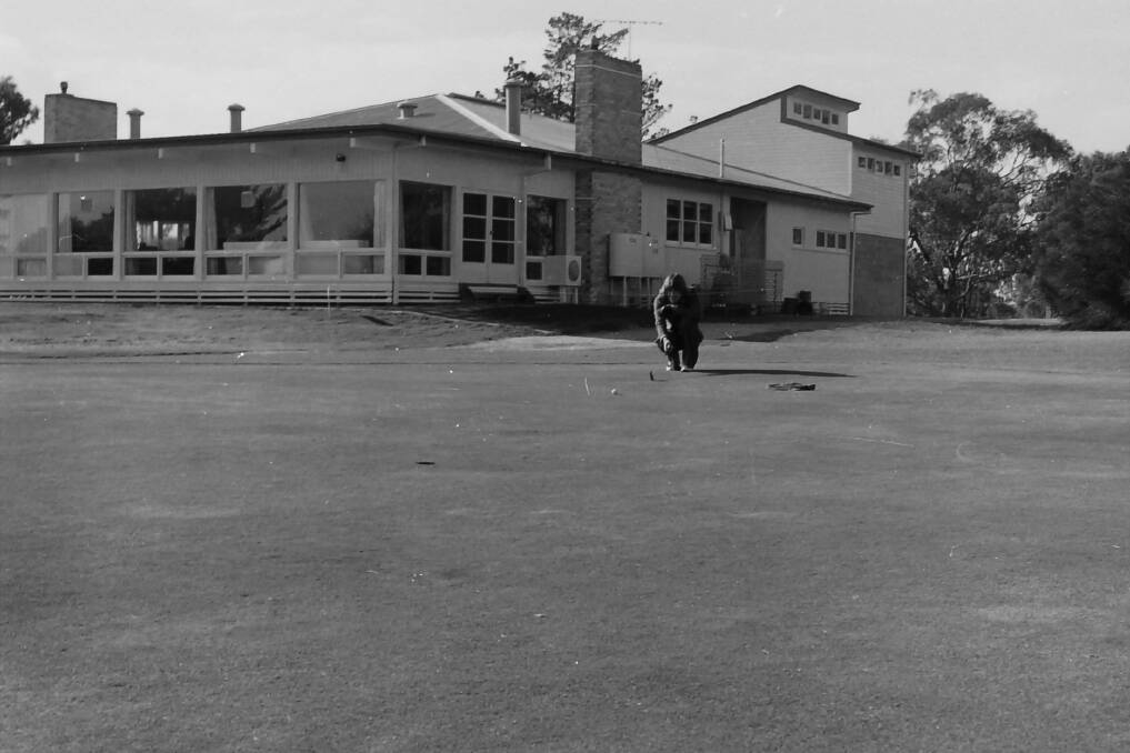 LOOKING BACK: A golfer sets up a shot on the green in front of the original clubhouse in 1977. 