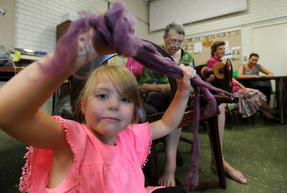MINI SPIN: Willow Martin, 4, plays with mohair fl eece as Mary Starick spins at a Spinners and Weavers open day in the Mibus Centre. Picture: PAUL CARRACHER