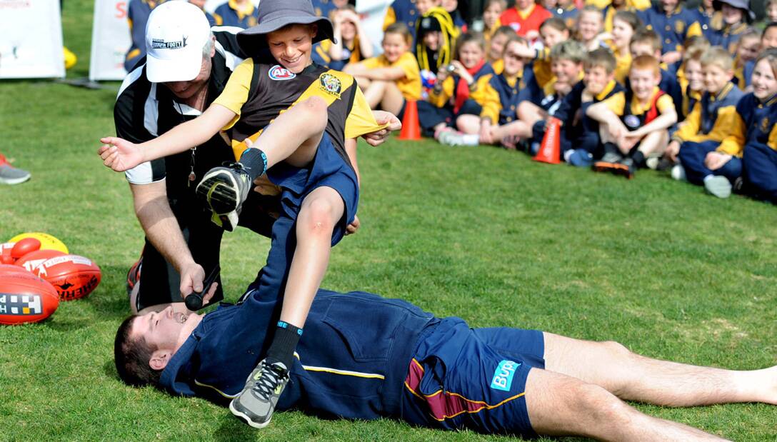 Brisbane Lions’ triple premiership player Jonathan Brown bench presses Horsham West Primary School youngster Connor Drum, 10, during a Toyota Good For Footy tour visit Horsham on Wednesday. More than 100 students, staff and parents attended the event, with past and present AFL stars hosting a fun-fi lled football clinic. Picture: SAMANTHA CAMARRI