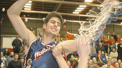 ELATION: Tim Wade cuts down the net while being hoisted by his Hornets teammates after the side downed Warragul in 2003. Picture: FILE