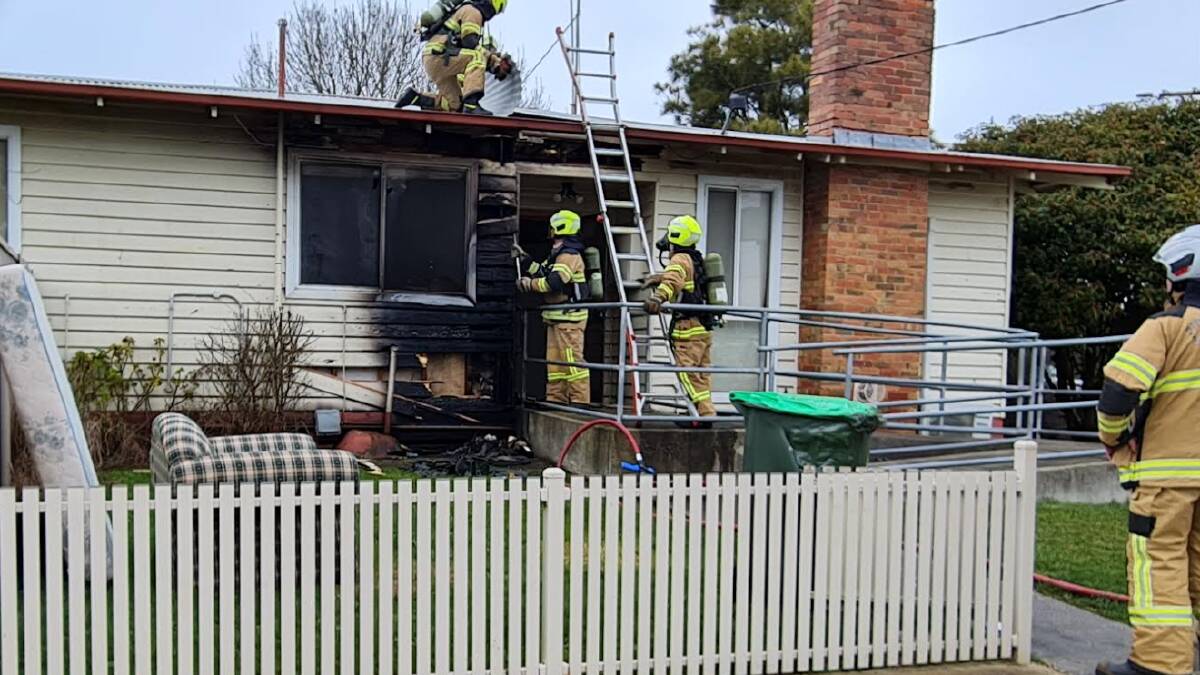 HOTSPOTS: Firefighters remove corrugated iron over the roof cavity, which was still smouldering, leaving a cloud of smoke over nearby residential blocks. Picture: Gabrielle Hodson.