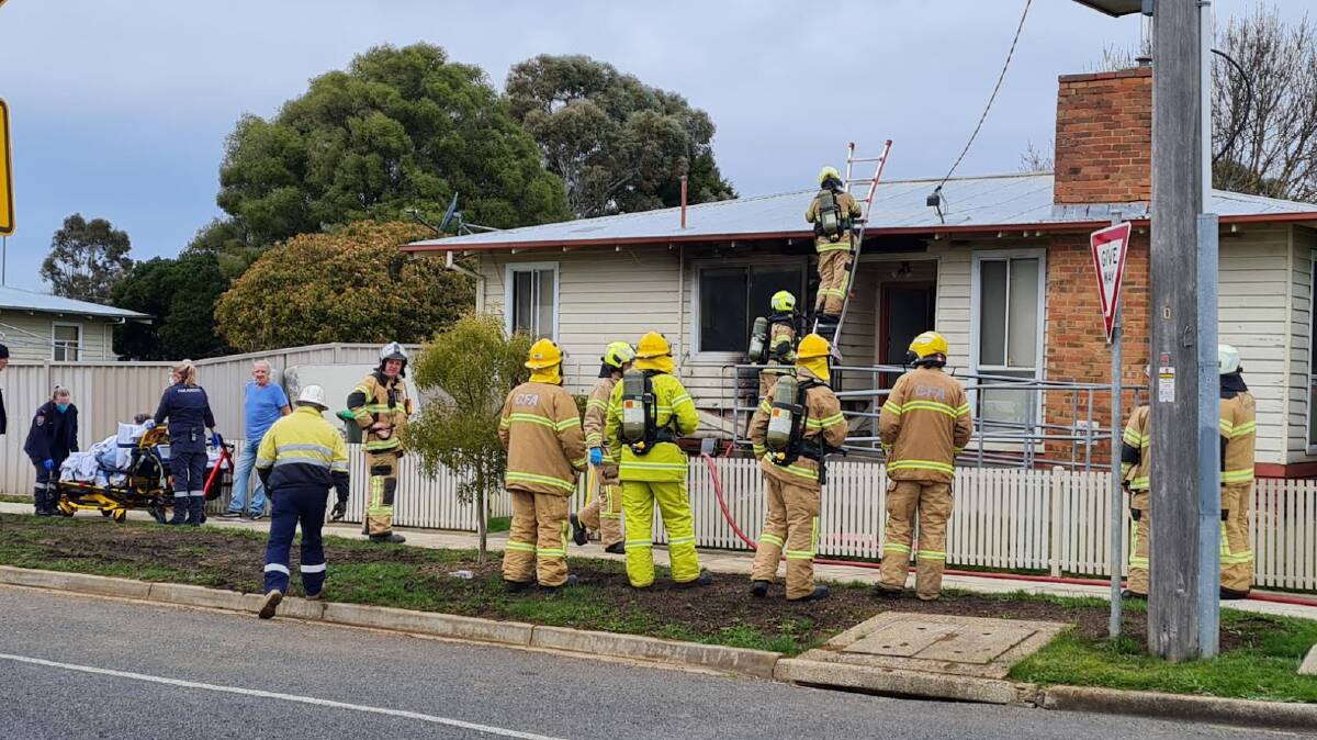 CUT OPEN: Firefighters prepared to open the roof of a home in Wendouree West after a fierce bin fire. Picture: Gabrielle Hodson.