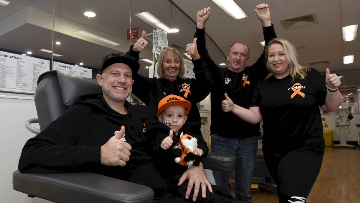 PLEASE DONATE: River and his dad Rodney gathered with 'Team River' at the blood donor centre in Redan, which was decorated in black and orange for the day. Picture: Lachlan Bence.