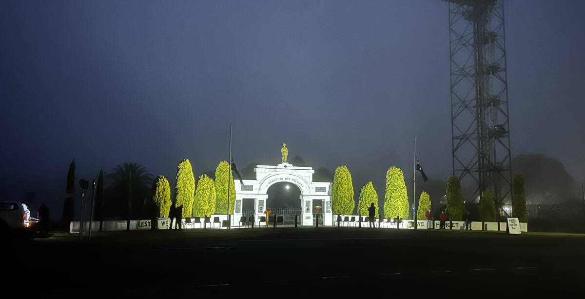 Pre-dawn, the Murtoa Memorial Gates are lit by flood lights as a crowd gathers in cold darkness on Anzac Day. Picture by John Hall