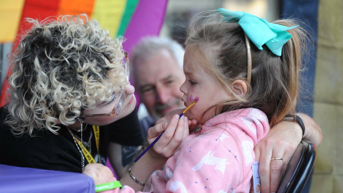 COLOURFUL COMMUNITY: Wimmera Pride Project's Lily paints glitter hearts on Ellie Murphy while Jeff Allan watches. Picture: ELIZA BERLAGE