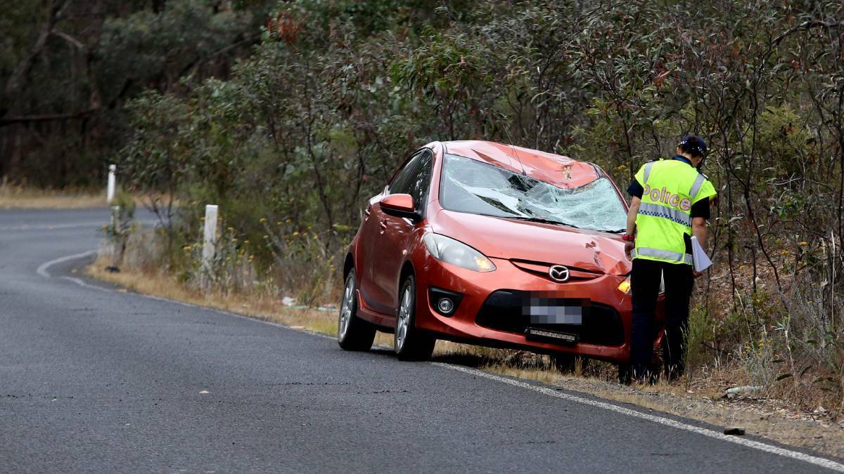 A police officer inspects a damaged car that hit cyclist Jason Lowndes, killing the 23-year-old on Sedgwick Road near Bendigo last Friday. Picture: Glenn Daniels