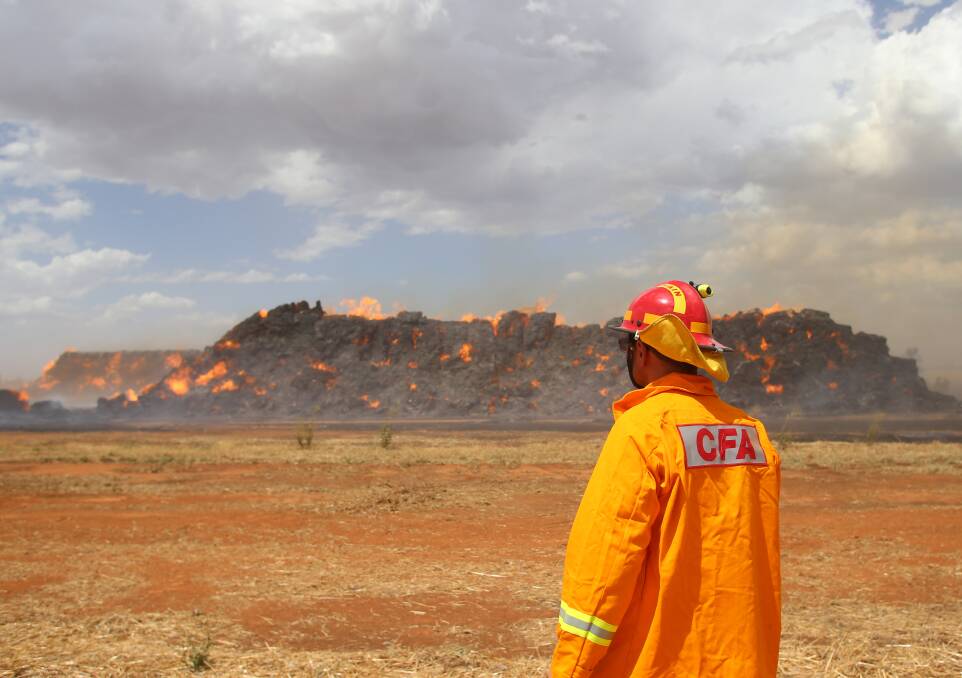 A firefighter looks out at thousands of haystacks burning at a property in western Victoria. Picture by Glenn Daniels