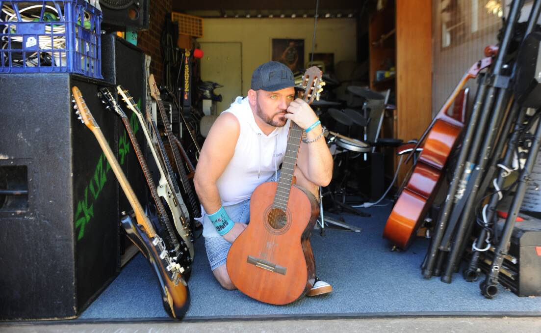 LIFE SAVER: Simon "Skuzz" Skurrie says music saved his life, after his mental health suffered when he lost the use of three fingers. He is pictured here holding his mother's old guitar, on which he started learning to play after several years of health problems. Picture: ALEXANDER DARLING