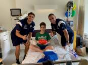 Fletcher Dandy, 9, with North Melbourne Kangaroo players Kallan Dawson and Bailey Scott at the Royal Children's Hospital. Picture supplied