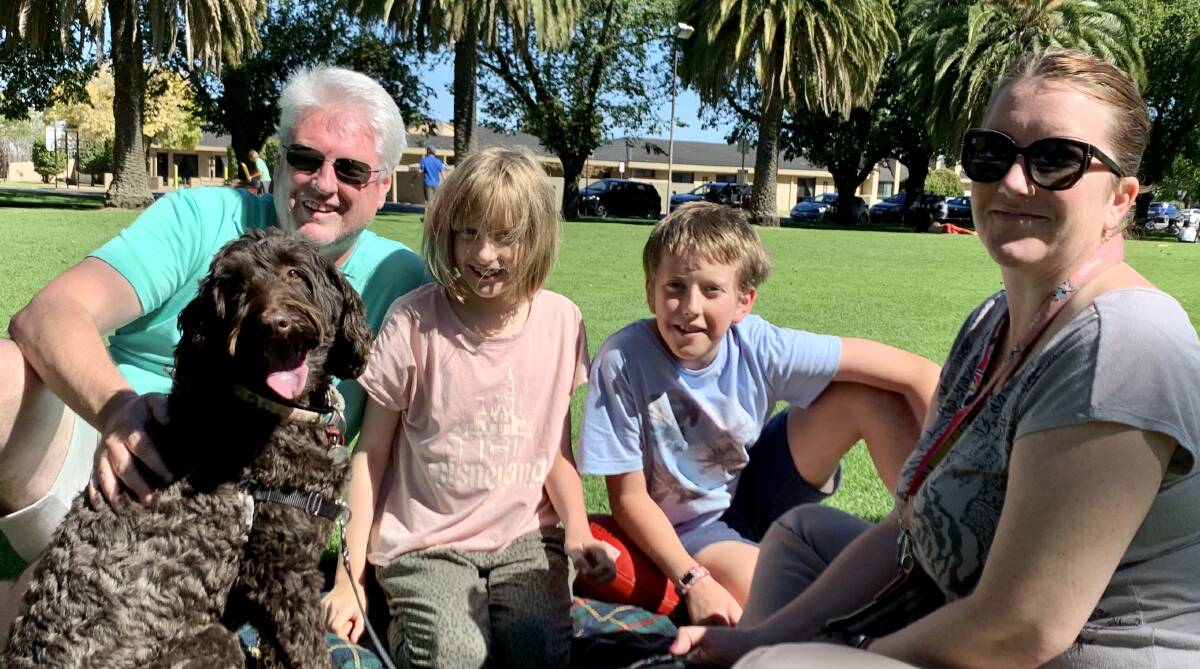 RELAXING: Melburnians Tim, Charli, Alex and Holly Duguid, and their labradoodle Coco, at Horsham's May Park on Monday. Picture: BEN FRASER