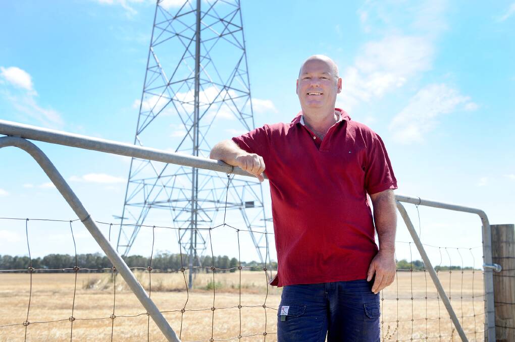 Wallup grain farmer Simon Tickner next to the high-voltage line that will be used in the Murra Warra Wind Farm project.