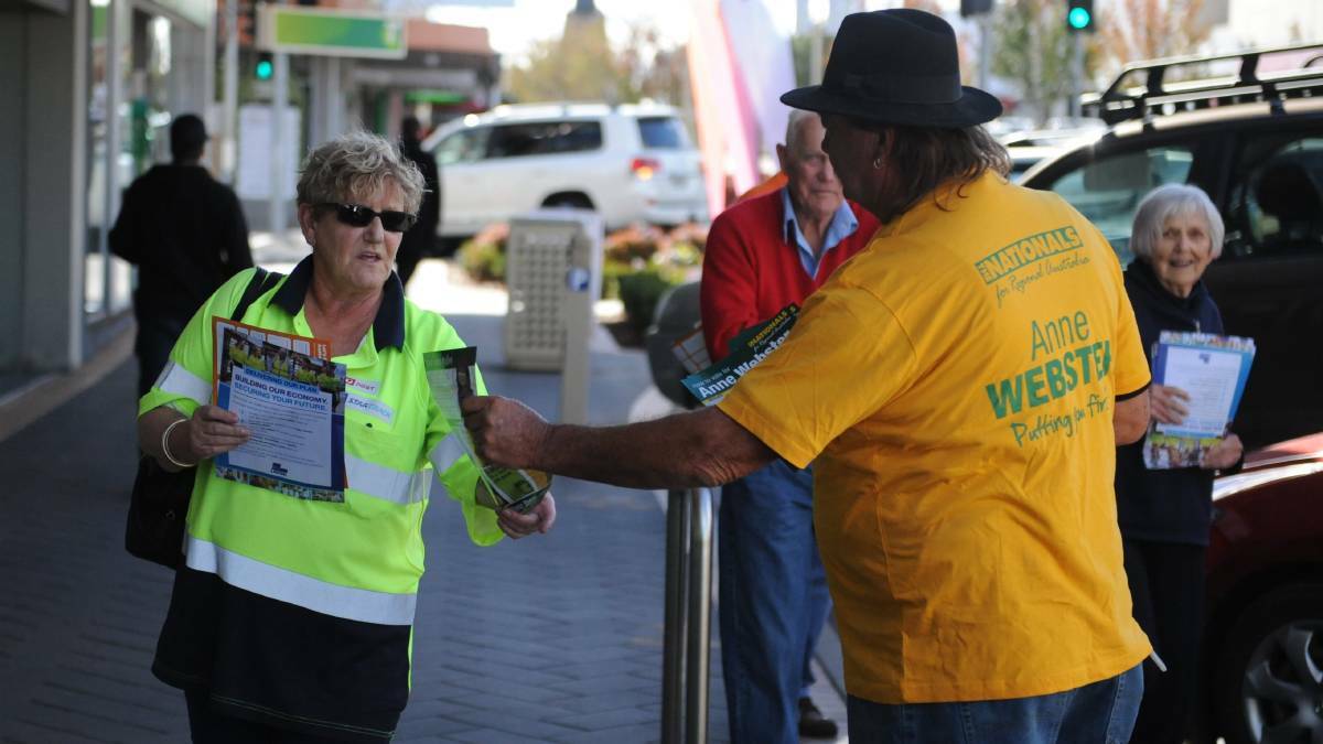 HOW TO VOTE: Warracknabeal's John Elliott, a National Party volunteer hands a card to an early voter on Firebrace Street on Monday. Picture: ALEXANDER DARLING