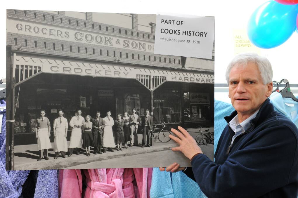 John Latimer with a photograph of the original Cooks store when it first opened in 1928. Picture: JADE BATE