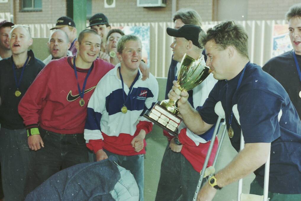 1997 premiership winning coach Ross McFarlane drinks from the trophy. 