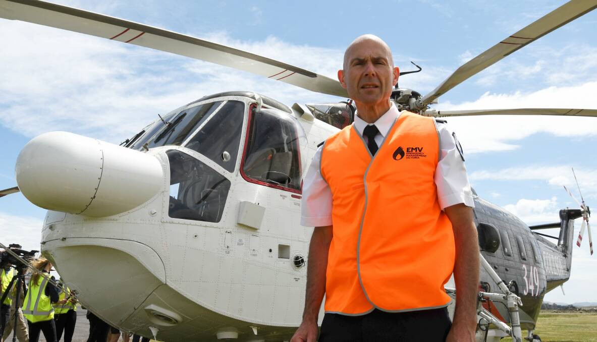 READY: Emergency Services commissioner Andrew Crisp at Ballarat airfield with one of the two firebombing helicopters approved to fight fires after dark. Picture: LACHLAN BENCE 