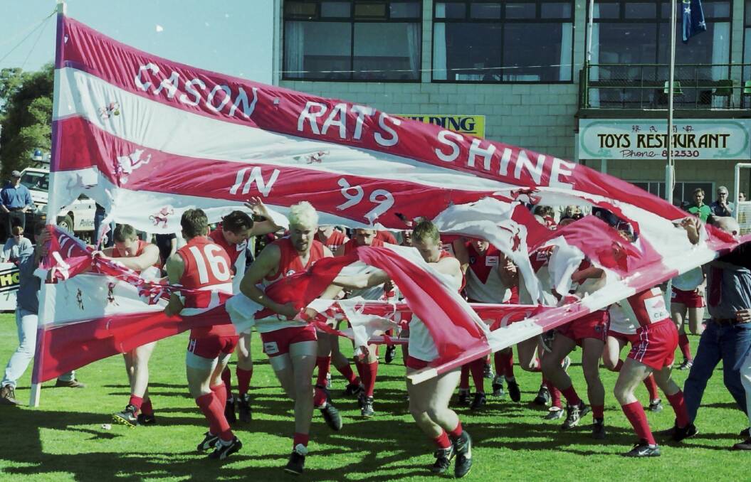 The Rats run through the banner on grand final day.
