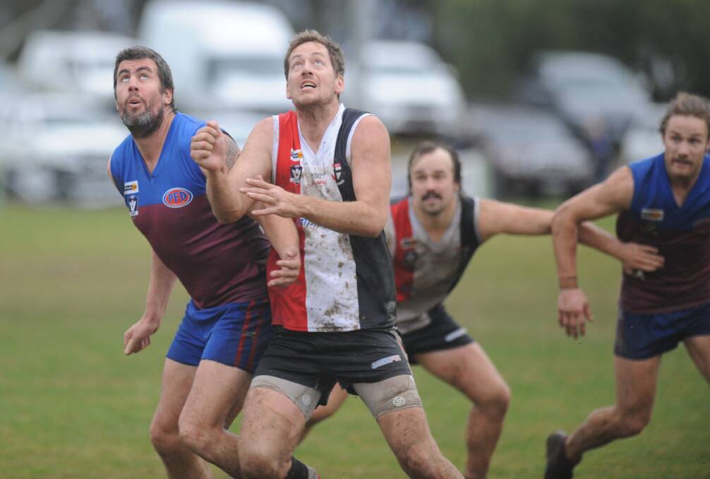 Horsham co-coach Tim Wade battles Michael Rowe in a ruck contest, with Saint Sam Clyne and Horsham co-coach Deek Roberts in position.